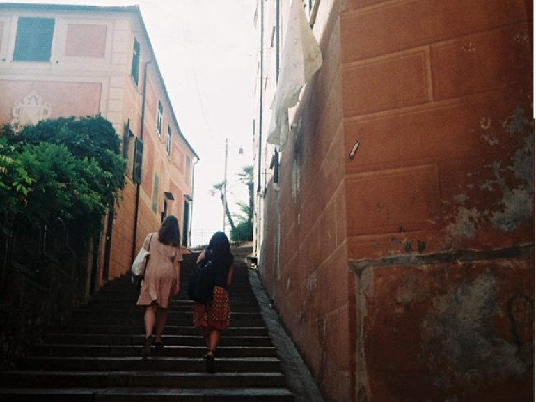 Dos niñas van a subir un tramo de escalones entre los edificios del centro histórico de Camogli
